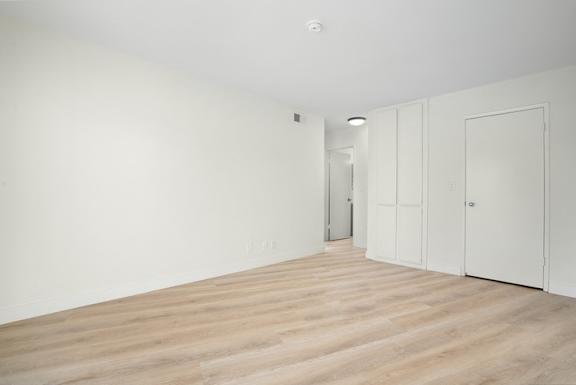A room with white walls and wooden flooring with two doors.