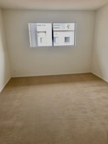 A room with a carpeted floor and a wall-mounted monitor displaying a webpage.