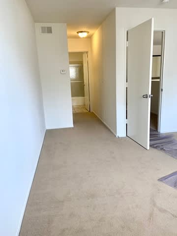 A hallway with a carpeted floor and white walls.