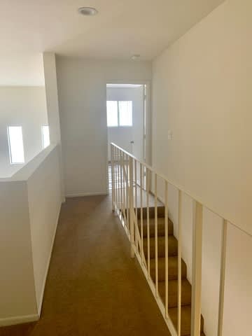 A long hallway with a staircase and a door at the end.