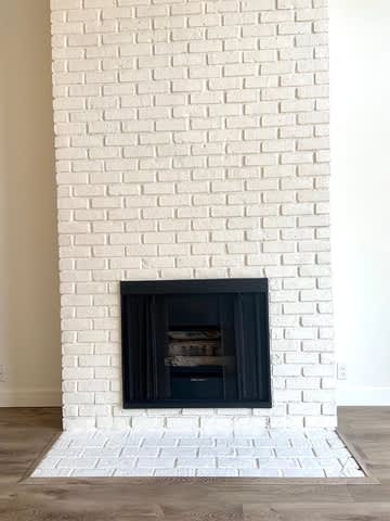 A white brick fireplace with a black firebox.