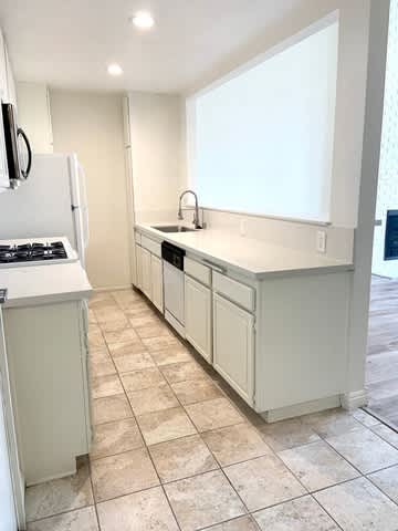 A kitchen with white appliances and cabinets.