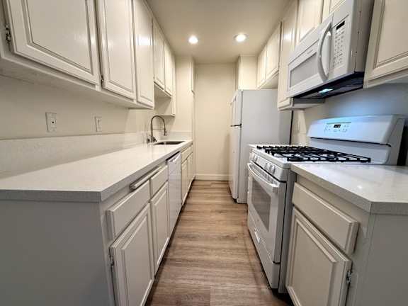 A kitchen with white cabinets and a white counter top.
