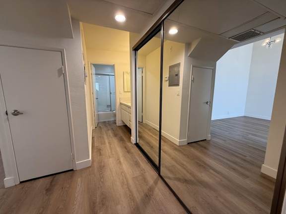 A hallway with a mirror on the wall and wooden flooring.
