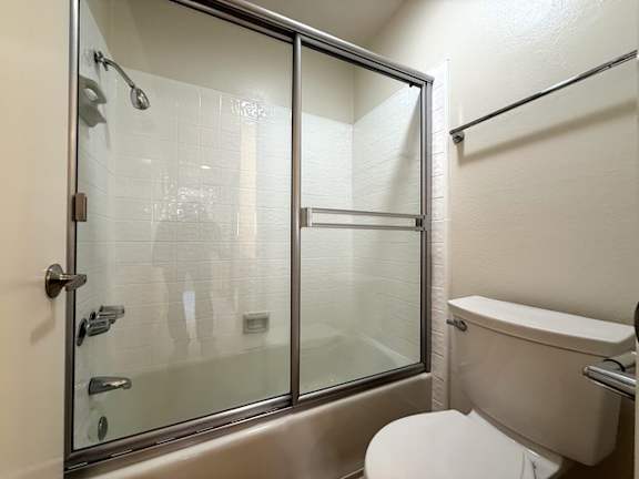 A white toilet sits next to a glass shower door in a bathroom.