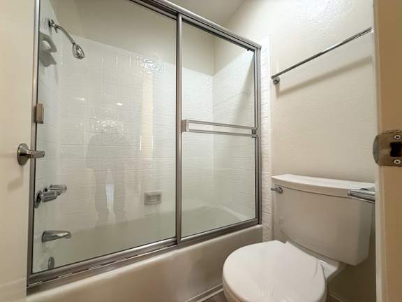 A person is taking a shower in a bathroom with a glass door.