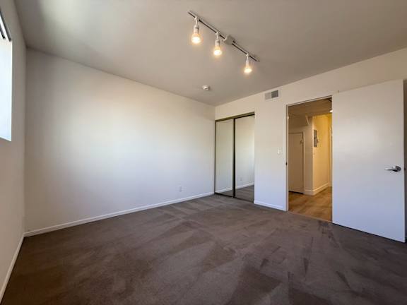 A room with a carpeted floor and a door on the right.