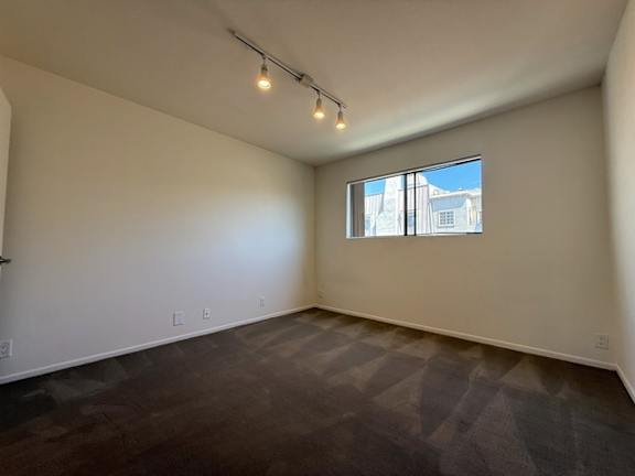 A room with a window and a carpeted floor.