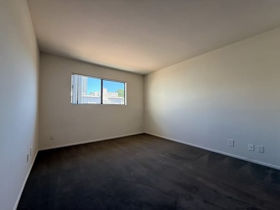 A room with a window and a view of a building outside.