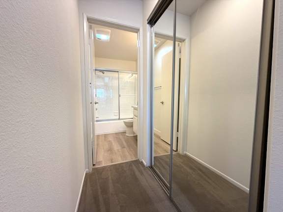 A hallway with a toilet visible through the door.