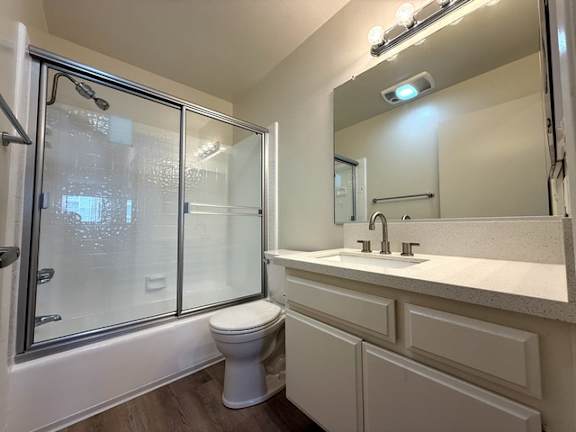 A white toilet sits in a bathroom next to a sink and a glass shower stall.