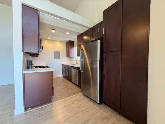 A kitchen with a refrigerator, cabinets, and a counter.