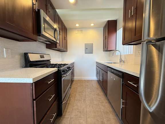 A kitchen with brown cabinets and stainless steel appliances.