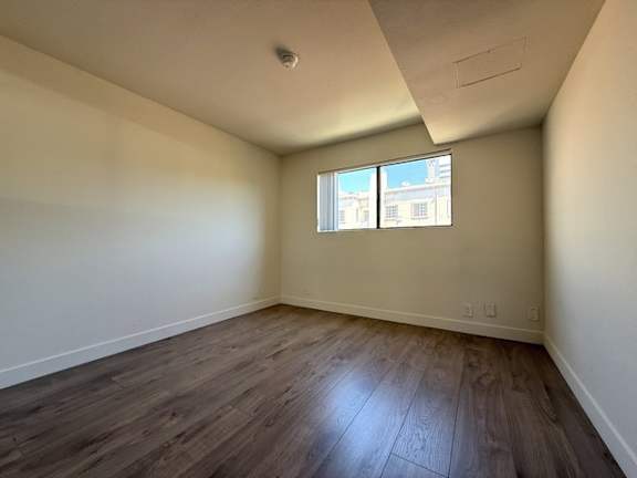A room with a window and wooden flooring.