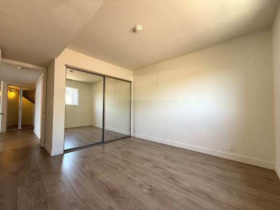 A room with a sliding glass door and wood flooring.