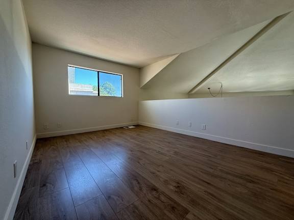 A room with wooden flooring and a window.