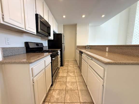 A kitchen with white cabinets and black appliances.