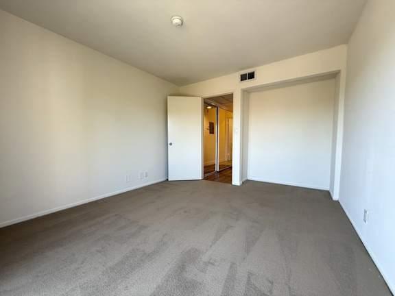 A room with a carpeted floor and a doorway leading to another room.