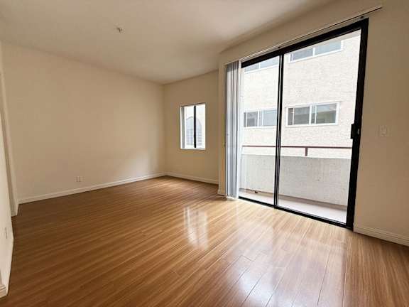 A room with wooden flooring and a sliding glass door.