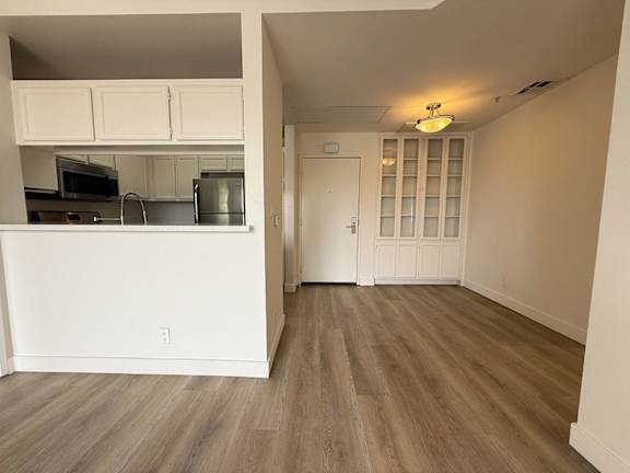 A kitchen with white cabinets and a wooden floor.