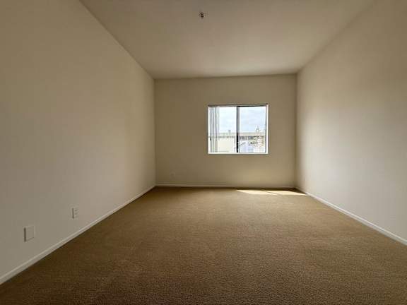 A room with a carpeted floor and a window.