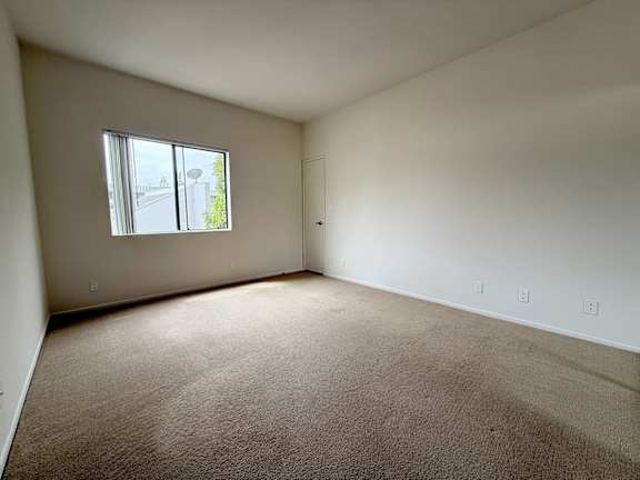 A room with a carpeted floor and a window.