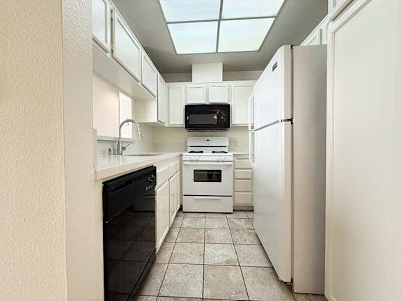 A kitchen with white appliances and a black oven.