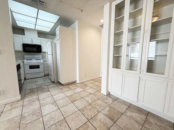 A kitchen with white cabinets and a microwave.