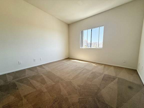 A room with a window and a carpeted floor.