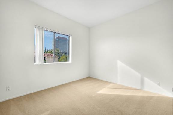 A room with a window and a view of a building outside.