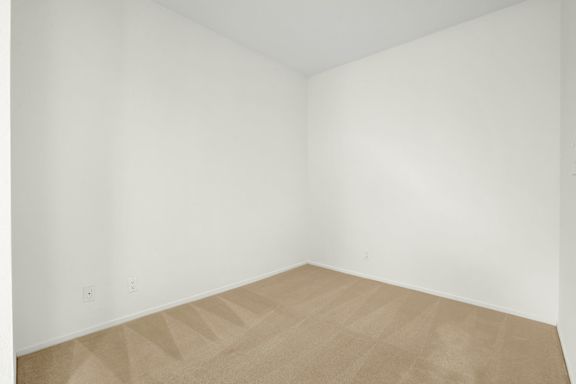A room with a tan carpet and white walls.