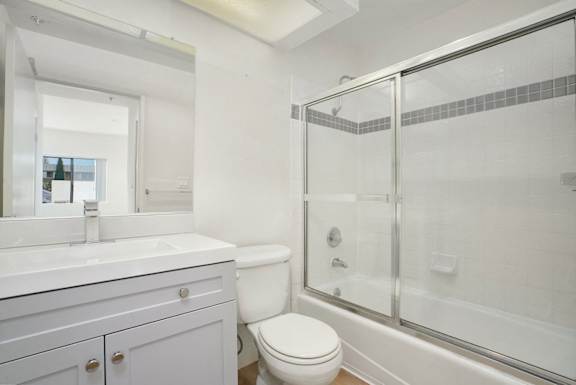 A white bathroom with a toilet, sink, and shower.