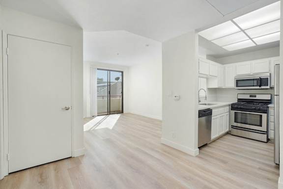 A kitchen with white cabinets and a wooden floor.