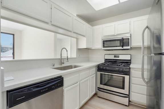 A modern kitchen with white cabinets and stainless steel appliances.