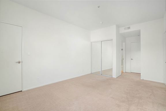 A large empty room with white walls and carpeted floor.