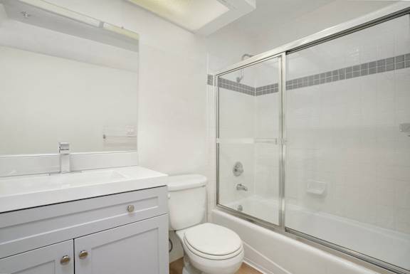 A white bathroom with a toilet, sink, and shower.