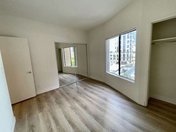 A room with wooden flooring and a large window.