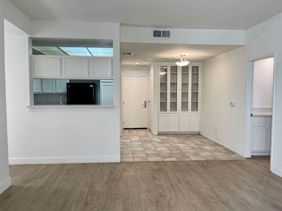 A kitchen area with a black fridge and white cabinets.