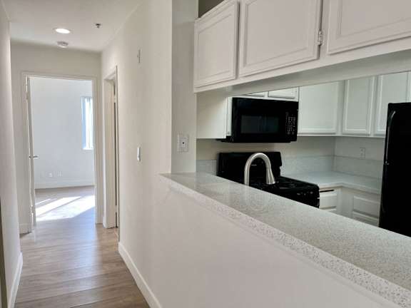 A kitchen with black appliances and white cabinets.