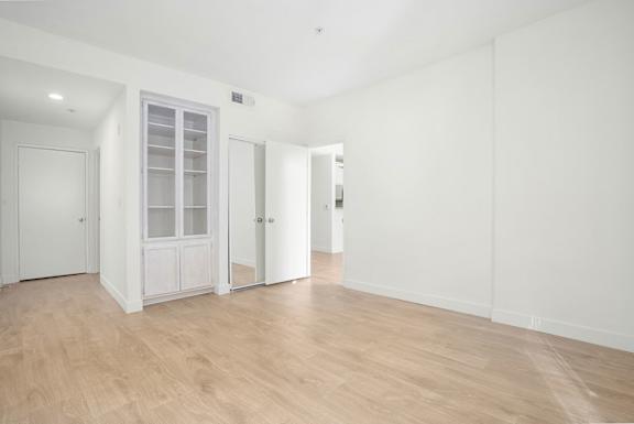 A room with a white door and a white cabinet with glass doors.