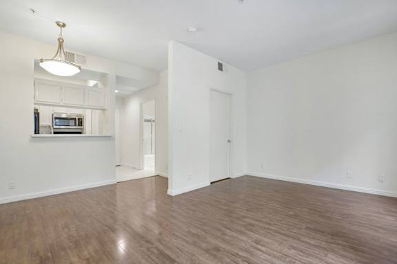 A large empty room with wooden floors and white walls.