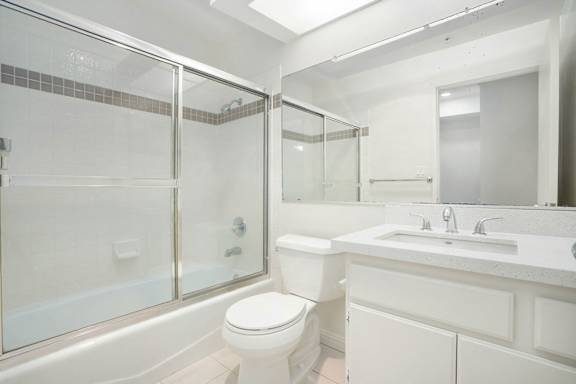 A white bathroom with a toilet, sink, and shower.