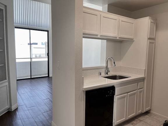 A kitchen with white cabinets and a black dishwasher.