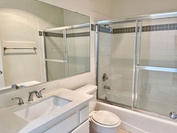 A white bathroom with a sink, toilet, and shower.