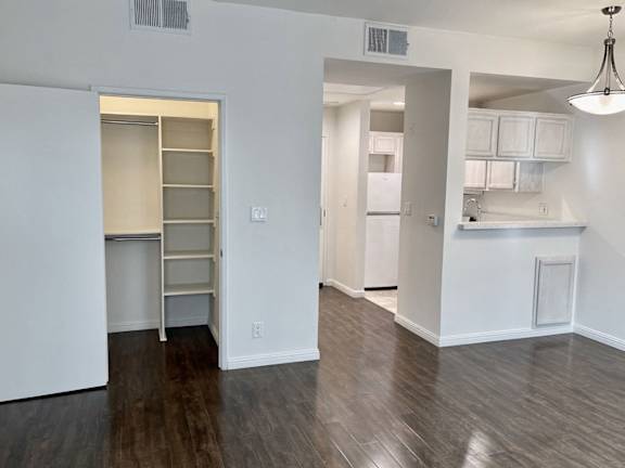A kitchen area with a refrigerator, cabinets, and a countertop.
