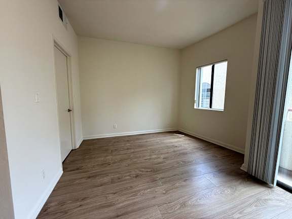 A room with wooden flooring and a window.