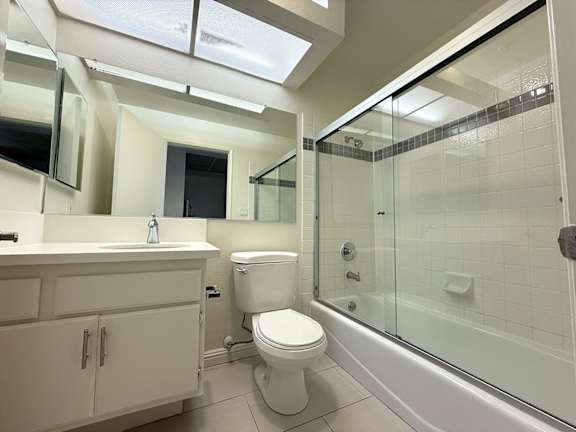 A white toilet is in a bathroom with a glass shower stall.