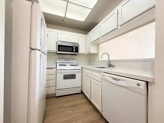 A kitchen with white appliances and cabinets.