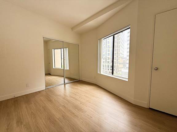 A large empty room with a wooden floor and a large mirror on the wall.