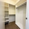 A white hallway with a door on the right and a shelf on the left.